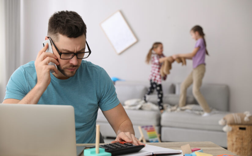 Children disturbing stressed man in living room. Working from ho