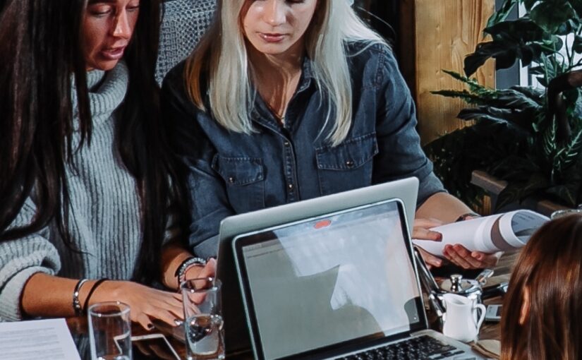 Group of people working on business project at cafe, sitting at table with sheets of paper and laptop