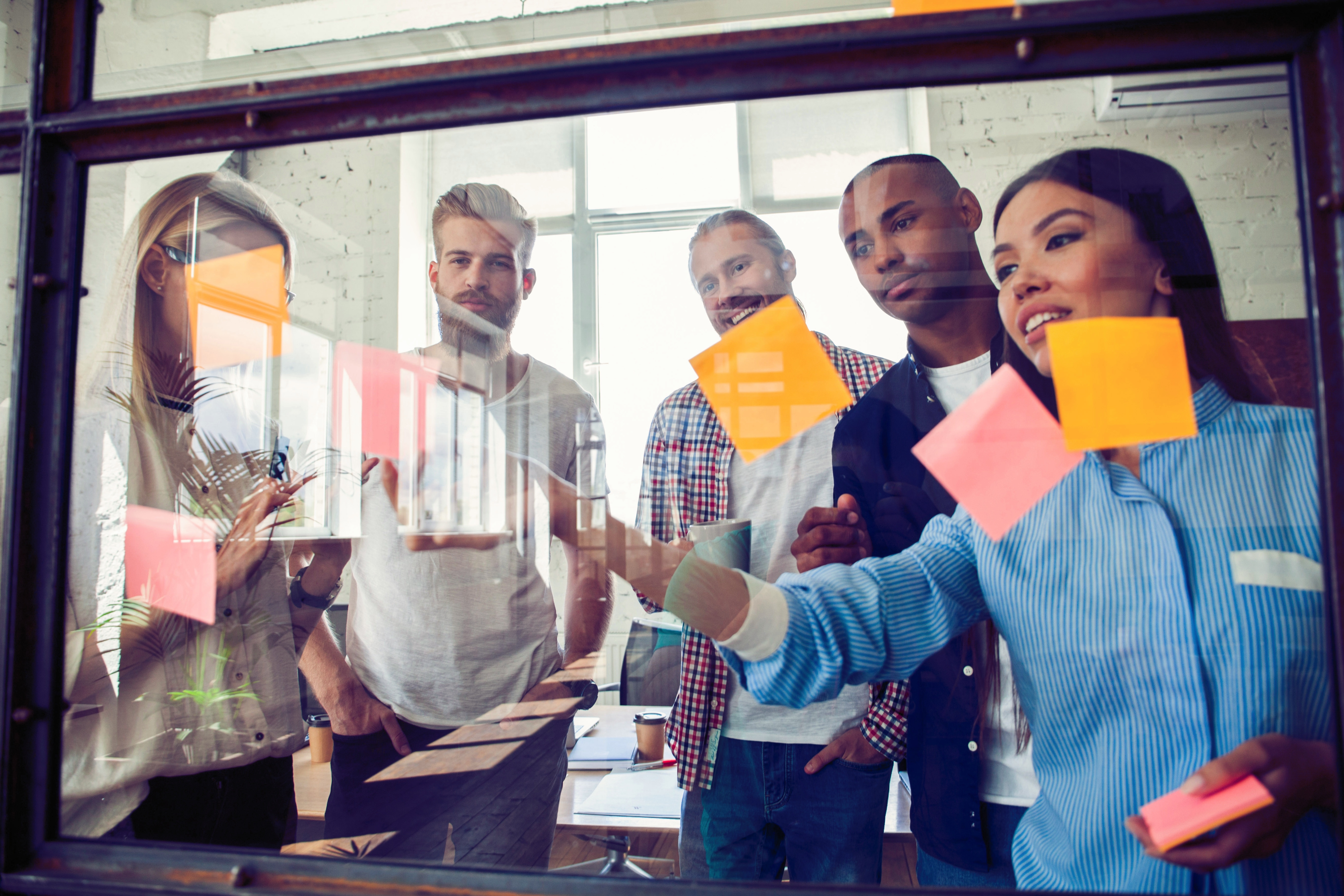 Business people meeting at office and use post it notes to share idea. Brainstorming concept. Sticky note on glass wall