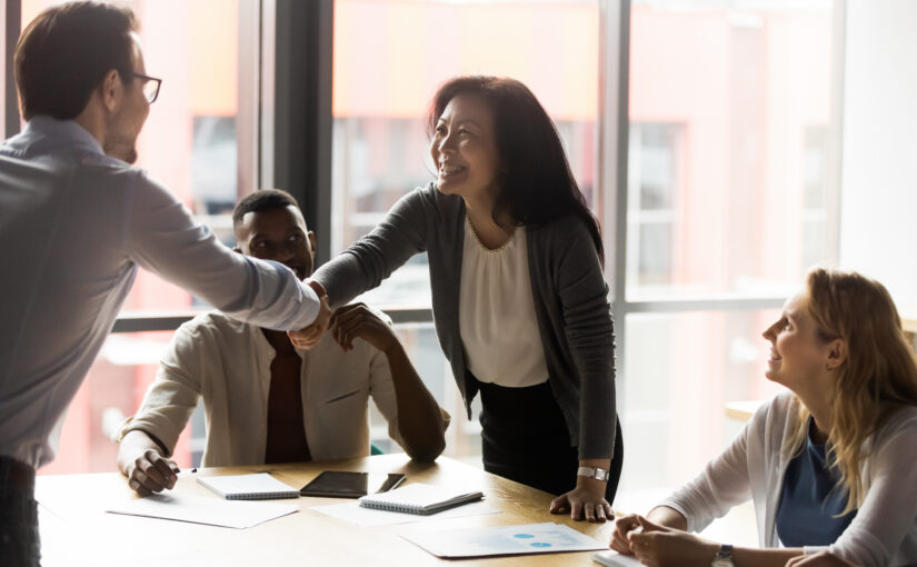 Middle-aged asian businesswoman shake hands with european millennial client