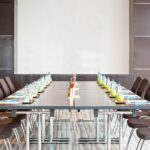 A meeting room set up with chairs, a table, water, fruit, and a screen.